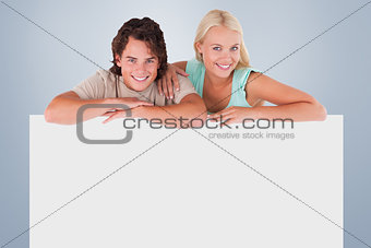 Composite image of cute couple leaning on a whiteboard