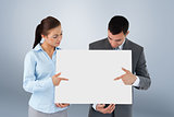 Composite image of business partners pointing at sign they are presenting