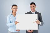 Composite image of business partners presenting sign together