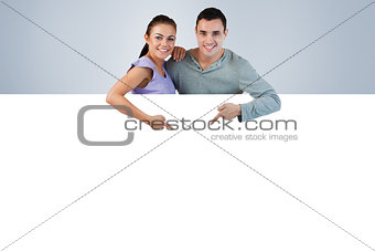 Composite image of young couple pointing at advertisement below them