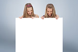 Composite image of close up of two young women holding a blank board