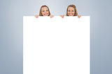 Composite image of close up of young women behind a blank sign
