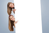 Composite image of portrait of two long hair students pointing behind a blank sign