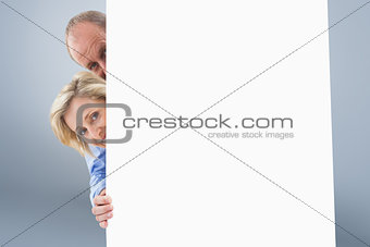 Composite image of mature couple smiling behind wall