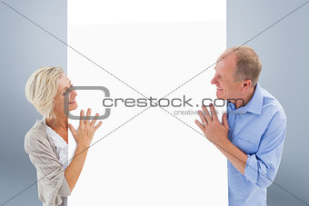 Composite image of mature couple smiling and holding card