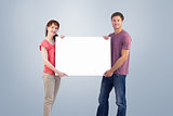 Composite image of couple holding a white sign