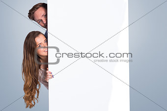 Composite image of portrait of young couple with blank board