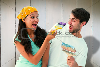 Composite image of happy young couple painting together and laughing