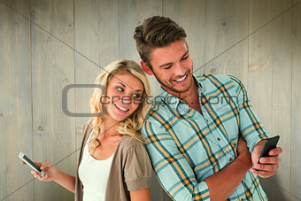 Composite image of attractive couple using their smartphones