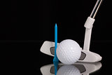 Golf putter and gold equipments on the black glass desk