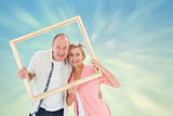 Composite image of older couple smiling at camera through picture frame