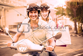 Hip young couple riding scooter with shopping bags