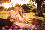Cute couple drinking white wine on a picnic smiling at each other
