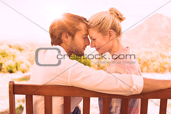 Cute couple sitting on bench together smiling at each other