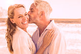 Man kissing his smiling partner on the cheek at the beach