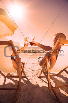 Couple clinking their glasses while relaxing on their deck chairs