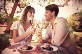 Cute happy couple sitting outside toasting with champagne with dessert