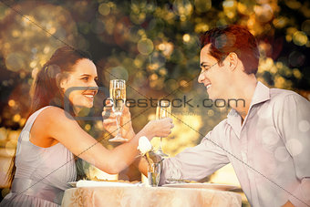Couple with champagne flutes sitting at outdoor café