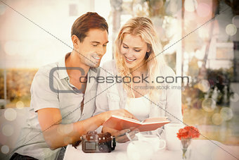 Cute hipster couple reading book together at table