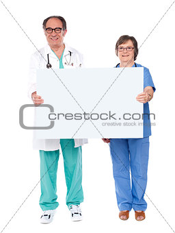 Aged doctors displaying white billboard