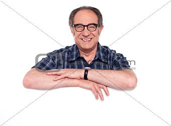 Smiling aged man posing with blank billboard