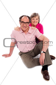 Smiling senior couple seated on floor. Posing