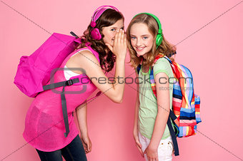 Trendy schoolgirls sharing a secret