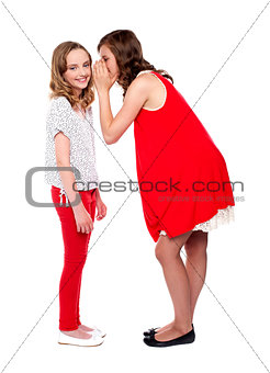 Girl whispering a secret into her friends ear