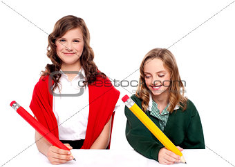 Cheerful girls writing with pencil on surface