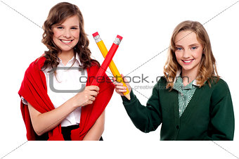 Smiling teenagers making cross sign with pencil