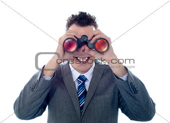 Smiling businessman looks through binoculars
