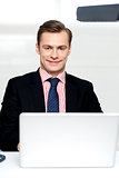 Attractive smiling man operating a laptop