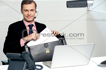 Male call centre executive arranging paper works