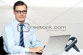 Handsome corporate male tying on laptop