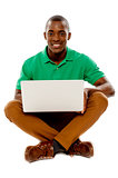 Cool guy seated on floor using laptop