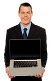 Smart businessman displaying laptop to you