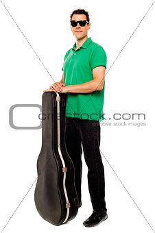 Trendy young man posing with guitar case