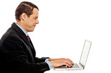 Side view of corporate male typing on laptop