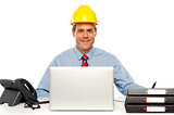 Architect wearing safety hat and using laptop