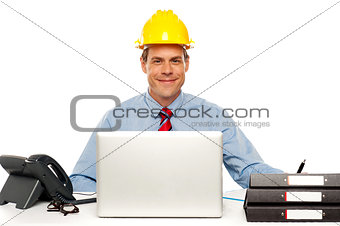 Architect wearing safety hat and using laptop