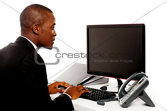 Male executive typing and looking at lcd screen