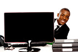 Businessman peeping from behind lcd monitor