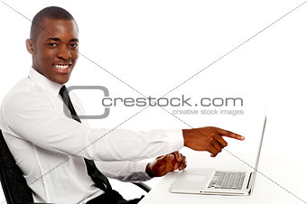 Smiling young african indicating on laptop screen