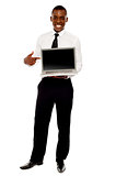 Cheerful male executive pointing at open laptop