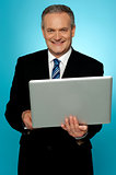 Smiling aged executive holding laptop