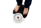 Woman standing on weighing scale, closeup of legs