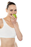 Pretty fit trendy woman eating fresh green apple