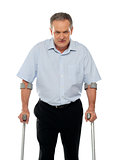 Angry aged man with crutches looking at you