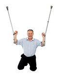 Cheerful senior man holding crutches upwards