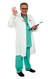 Male physician with excellent gesture holding clipboard
